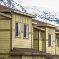 Square Row of cream colored homes with snow covered mountain and cloudy sky background Royalty Free Stock Photo