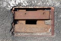 Square rusted iron drain opening with missing grates cover surrounded with cracked asphalt Royalty Free Stock Photo