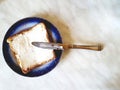 Square sandwich on a plate with a blue border and a knife. White background with gray divorces. Royalty Free Stock Photo