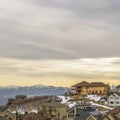 Square Scenic winter view of houses on a snowy mountain against cloudy sky at sunset