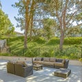 Square Seating area on the patio of a house surrounded by lush foliage and metal gate