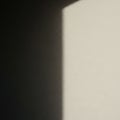 A square shadow falls on a textured wall, dividing light and dark areas Royalty Free Stock Photo