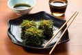 square-shaped plate with seaweed salad beside lacquerware chopsticks