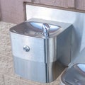 Square Shiny metal drinking fountain for children and adults mounted on building wall Royalty Free Stock Photo
