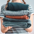 Square shot of a Girl teenager with two braids holding a pile of clothes, isolated on gray background Royalty Free Stock Photo