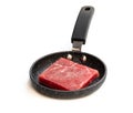 Square slice of raw beef meat on small frying pan isolated on white Royalty Free Stock Photo