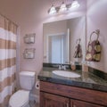 Square Small bathroom interior with dark wood vanity sink and black granite countertop Royalty Free Stock Photo