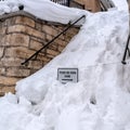 Square Snowed in stairs amid stone retaining wall with home and cloudy sky background