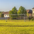 Square Soccer goal on vast green grassy field in front of houses viewed on a sunny day Royalty Free Stock Photo
