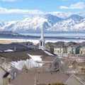 Square Spire of church towering over homes in the valley overlooking snowy mountain Royalty Free Stock Photo