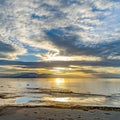 Square Striking cloudy sky over a calm lake that reflects the golden sun at sunset