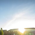 Square Sun in the vast blue sky shining brightly over beautiful multi storey houses Royalty Free Stock Photo