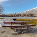 Square Table and benches at a snowy picnic area near a lake on a sunny winter day Royalty Free Stock Photo