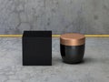 Square textured Black box with cosmetic container on concrete floor, golden cap