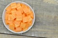 Square thin slices carrots on plate on wooden table