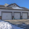 Square Three car garage with white doors and snowy driveway on a sunny winter day Royalty Free Stock Photo