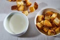 Square toasted pieces of homemade delicious rusk, hardtack, Dryasdust, zwieback and plate of milk on a white tablecloth