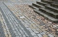 Colored cobblestone cube tiles of gray brown and black color laid in rows on the square. It creates the impression giant mosaic