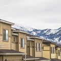 Square Townhouses with wall sidings and white garage doors against snowy mountain