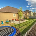 Square Trampoline at the sunny backyard of home with planting bed along picket fence