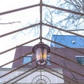 Square Vintage outdoor lamp hanging on the gable metal roof frame of a pergola