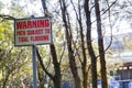 Square warning sign `Path Subject to tidal flooding` in a garden.