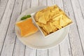 Square white bowl filled with corn nachos with cheddar sauce for dipping Royalty Free Stock Photo