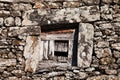 Square window with old wooden door in a rustic stone wall Royalty Free Stock Photo