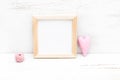 Square wooden frame and pink heart on a wooden background. Mock
