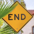 Square Yellow End sign and green palm tree leaves against sky and house with balcony Royalty Free Stock Photo