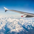 Squared image of a plane wing over snowy alpine mountains