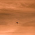 Squared image with a silhouette of parachutist at sunset