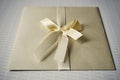 Squared silver envelope with pearly ribbon and topknot as an example of typical wedding invitation and wedding announcement cover