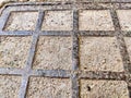 Squares in a metal grid lying on concrete, pebbles, earth. The old sidewalk or wall. A pattern of metal rods. Background