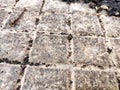 Squares in a metal grid lying on concrete, pebbles, earth. The old sidewalk or wall. A pattern of metal rods. Background