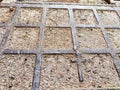 Squares in a metal grid lying on concrete, pebbles, earth. The old sidewalk or wall. A pattern of metal rods. Background