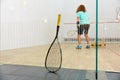 Squash racket leaned on net and sportspeople playing
