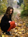 Squatting beauty girl in fall outdoor Royalty Free Stock Photo