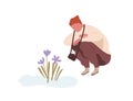 Squatting man admiring first spring flower or snowdrop. Teenager with camera sitting and looking at primrose. Flat