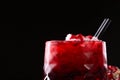 Squeezed pomegranate juice with crushed ice and black straws on a black background. Organic and benefit garnet beverage.