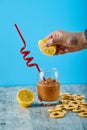 Squeezing fresh lemon into glass of juice with straw and crackers on gray table Royalty Free Stock Photo