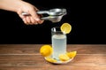Squeezing lemon into a glass of lemonade with yellow lemons around a white plate Royalty Free Stock Photo