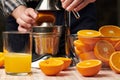 Squeezing an orange with a manual press, close view, making a glass of fresh. Fresh oranges on a wooden table, whole, squeezed and