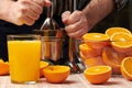Squeezing an orange with a manual press, close view, making a glass of fresh. Fresh oranges on a wooden table, whole, squeezed and