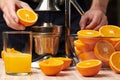 Squeezing an orange with a manual press, close view, making a glass of fresh. Fresh oranges on a wooden table, whole, squeezed and