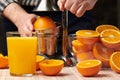 Squeezing an orange with a manual press, close view, making a glass of fresh. Fresh oranges on a wooden table, whole, squeezed and