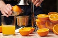 Squeezing an orange with a manual press, close view, making a glass of fresh. Fresh oranges on a wooden table, whole, squeezed and