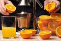 Squeezing an orange with a manual press, close view, making a glass of fresh. Fresh oranges on a wooden table, whole, squeezed and