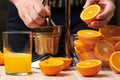 Squeezing an orange with a manual press, close view, making a glass of fresh. Fresh oranges on a wooden table, whole, squeezed and