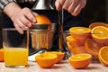 Squeezing an orange with a manual press, close view, making a glass of fresh. Fresh oranges on a wooden table, whole, squeezed and